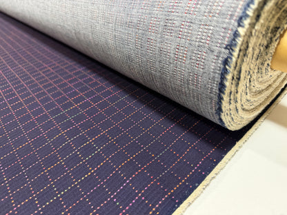 Okayama Denim 7 oz Sashiko Grid Cotton Fabric featuring colorful stitching and unique pattern, rolled and ready for use.