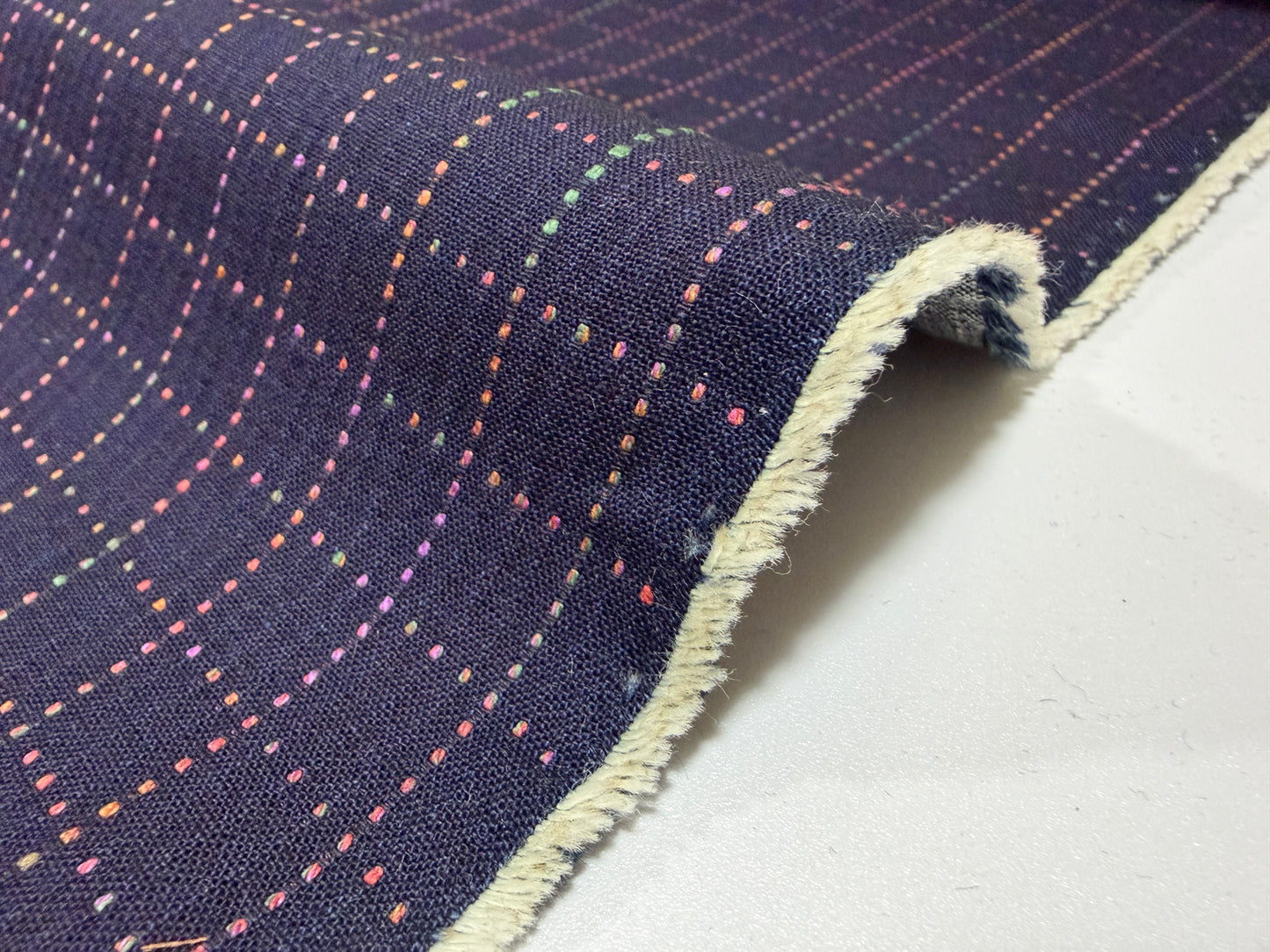 Okayama Denim fabric showcasing colorful multi-color stitching on a navy Sashiko grid pattern.
