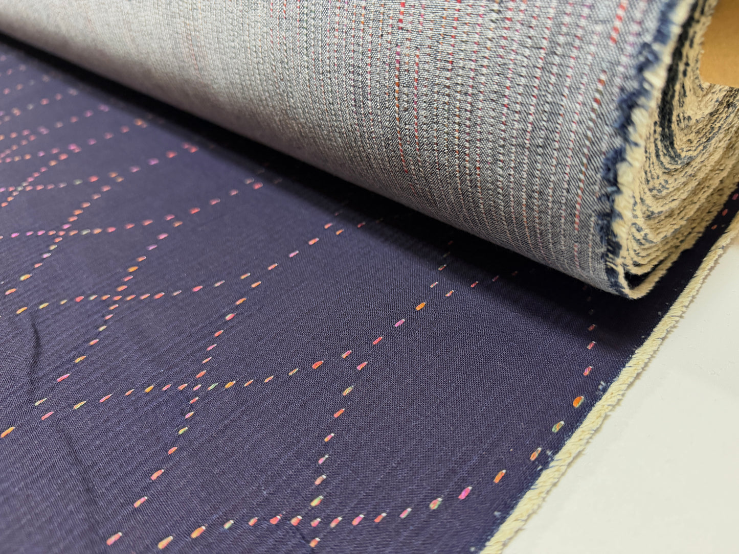 Okayama Denim 7 oz Sashiko "Diamond Lattice" Cotton Fabric with colorful stitching rolled on a bolt.