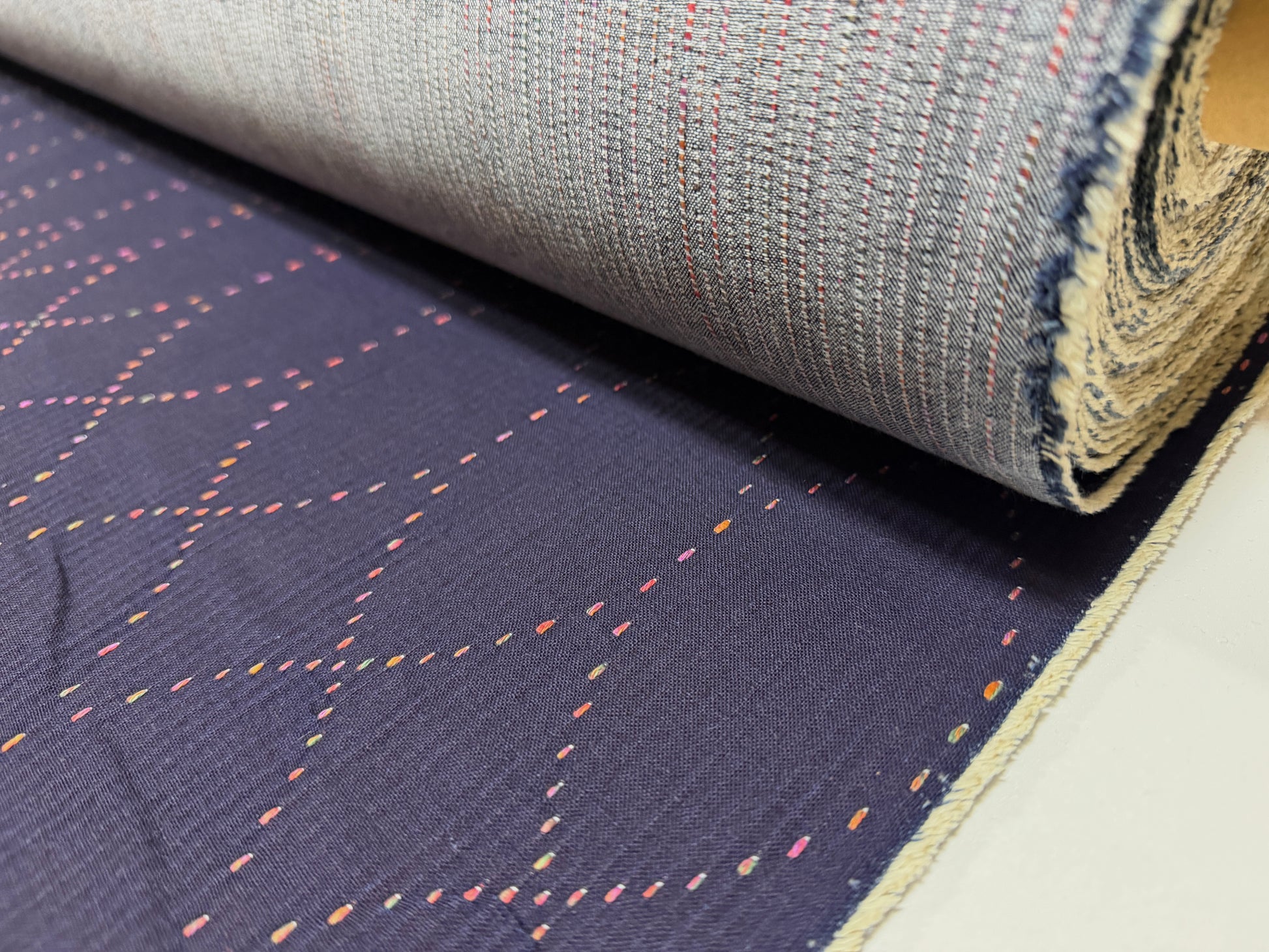 Okayama Denim 7 oz Sashiko "Diamond Lattice" Cotton Fabric with colorful stitching rolled on a bolt.