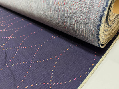 Okayama Denim 7 oz Sashiko "Diamond Lattice" Cotton Fabric with colorful stitching rolled on a bolt.