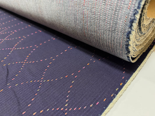 Okayama Denim 7 oz Sashiko "Diamond Lattice" Cotton Fabric with colorful stitching rolled on a bolt.