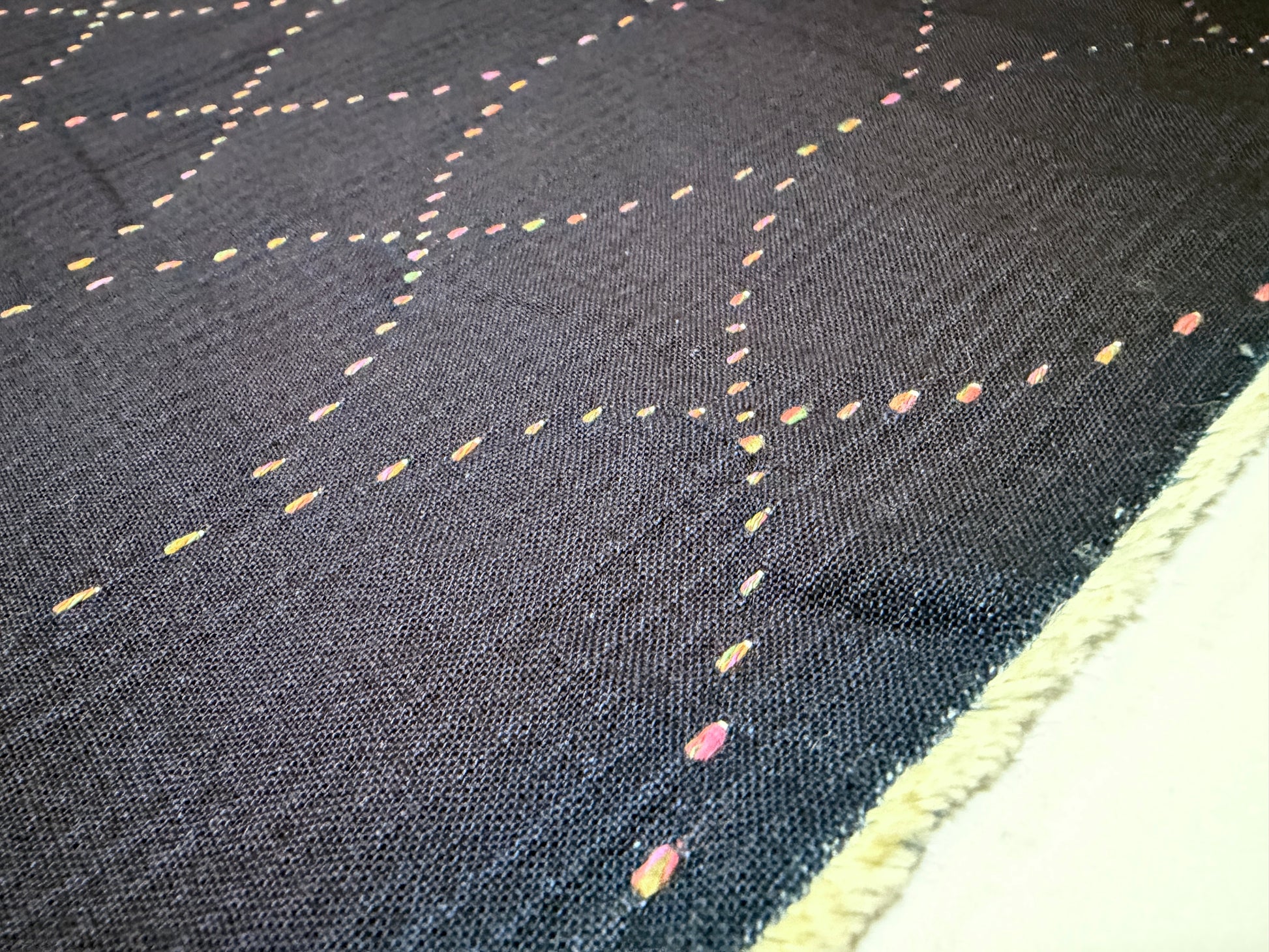 Okayama Denim 7 oz Sashiko fabric displaying colorful stitching on a dark background, perfect for unique textile projects.
