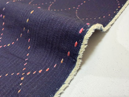 Okayama Denim 7 oz Sashiko Diamond Lattice cotton fabric showing colorful stitching detail on a dark background.