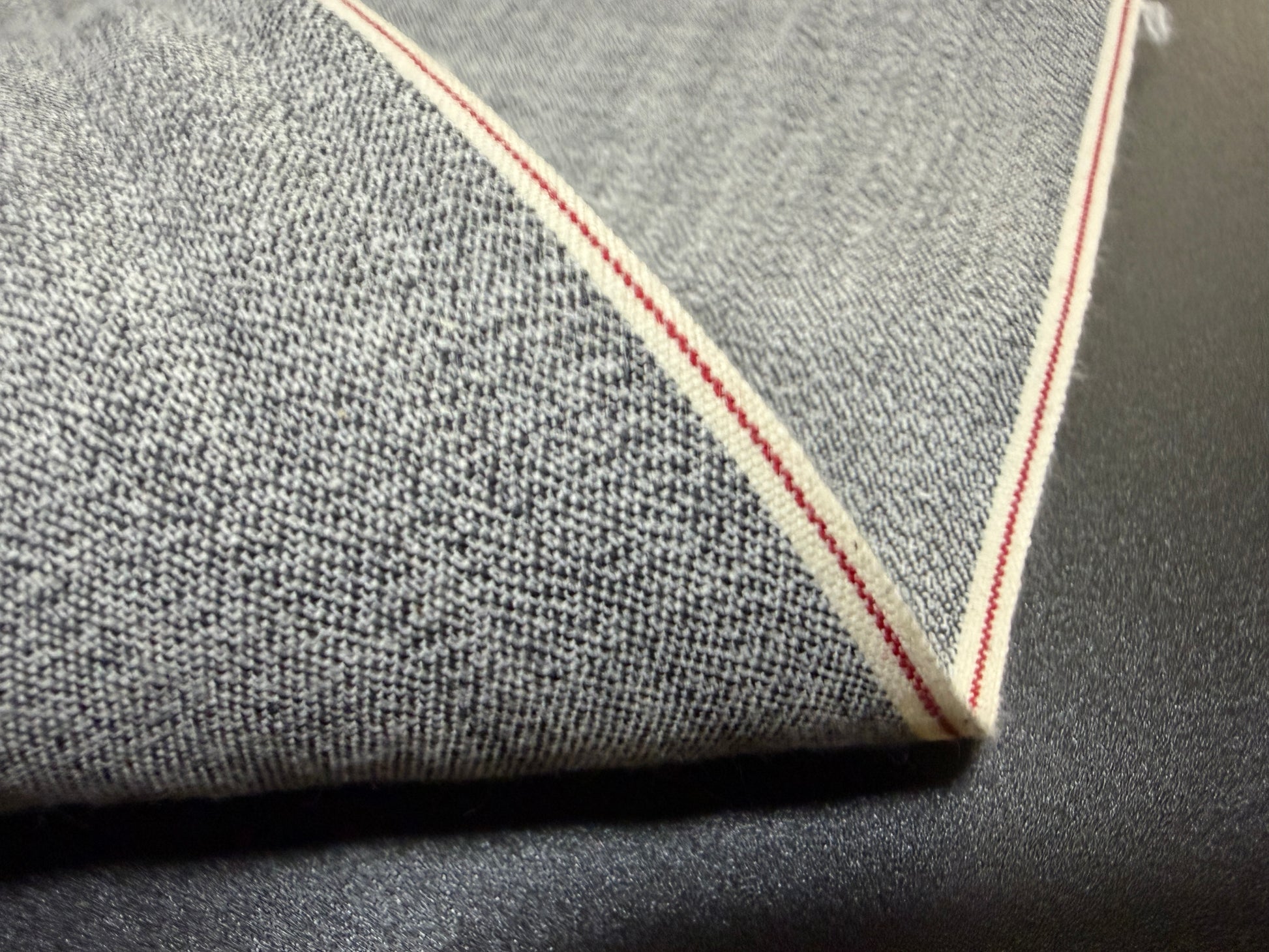 Okayama Denim 6 oz Japanese gray chambray fabric showing red selvage detail.