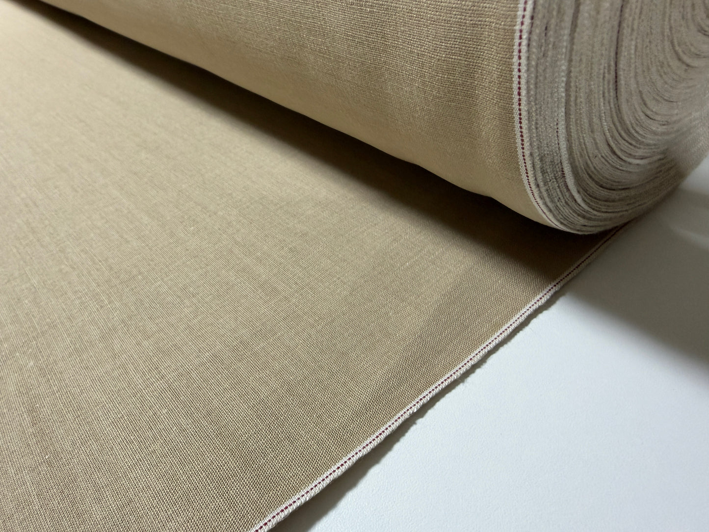 Okayama Denim - close-up view of 8 oz Japanese cotton beige dungaree fabric roll with selvage edge.
