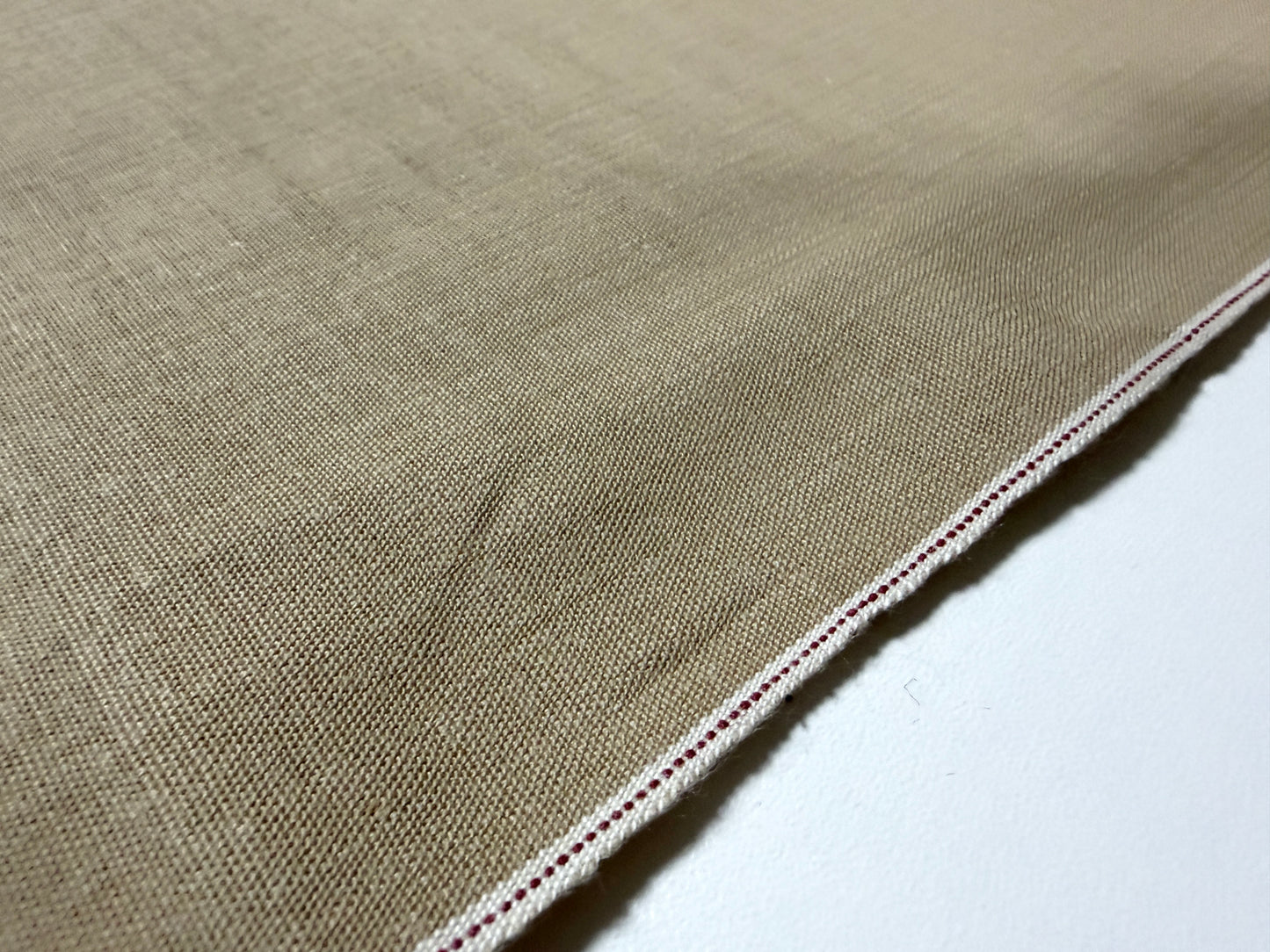 Close-up view of Okayama Denim 8 oz beige cotton dungaree fabric showcasing selvage edge.