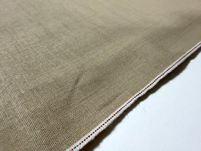 Close-up view of Okayama Denim 8 oz beige cotton dungaree fabric showcasing selvage edge.