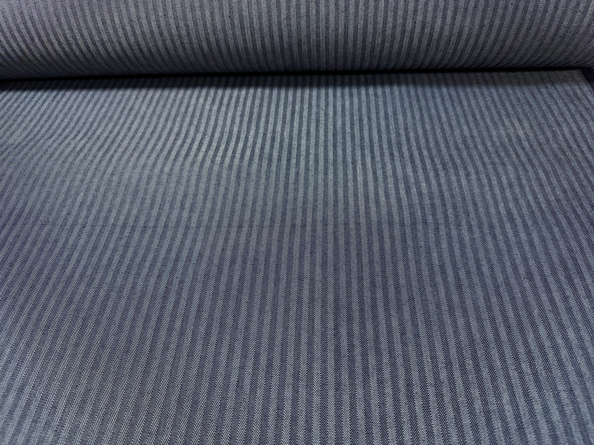 Okayama Denim fabric showing navy herringbone stripe pattern on a roll, 10.5 oz Japanese cotton material.
