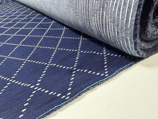 Okayama Denim fabric showcasing 7 oz blue & white Sashiko stitching pattern rolled on a table.