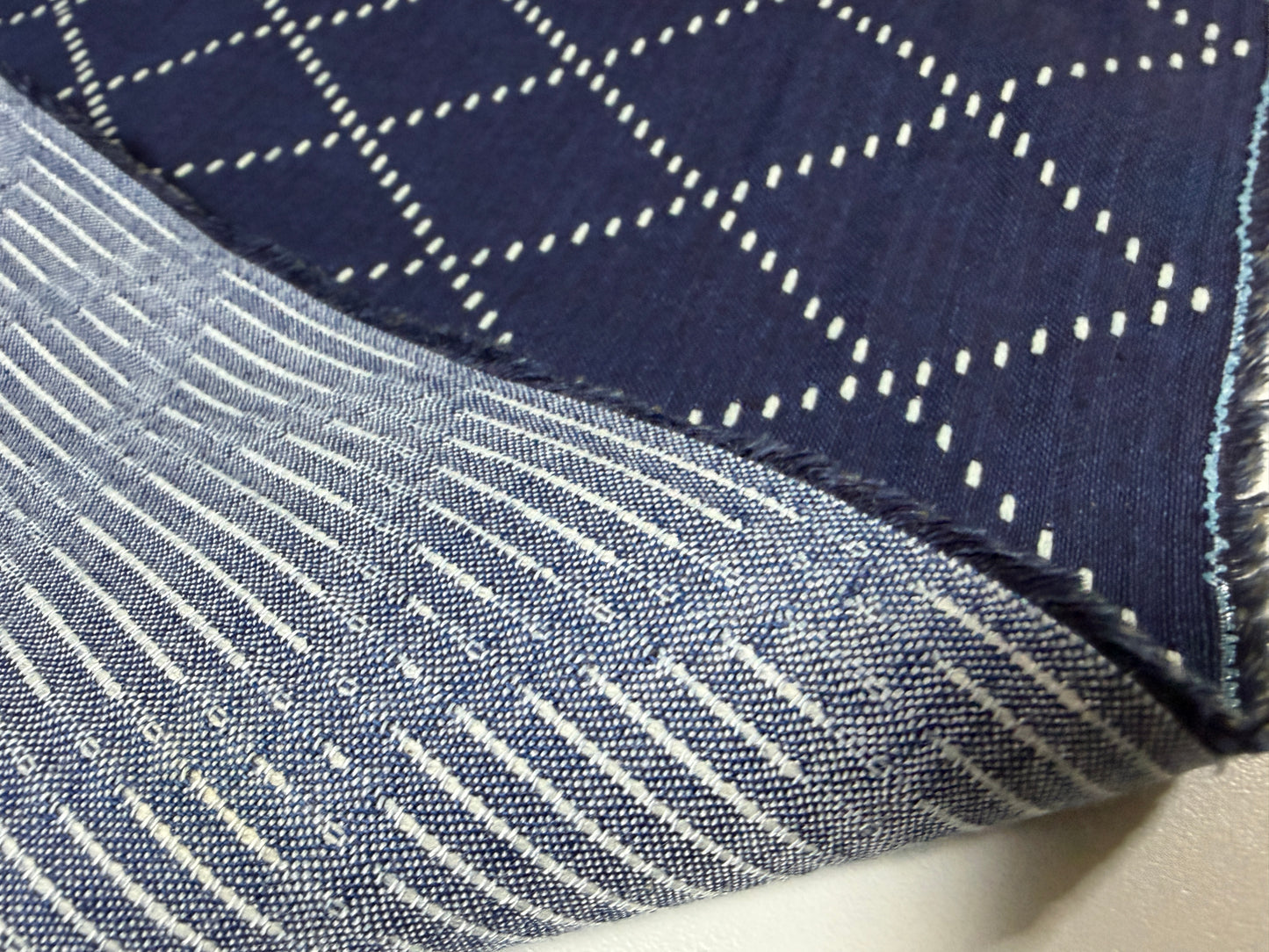 Close-up of Okayama Denim fabric showcasing blue and white Sashiko stitching patterns, ideal for sewing and crafting.