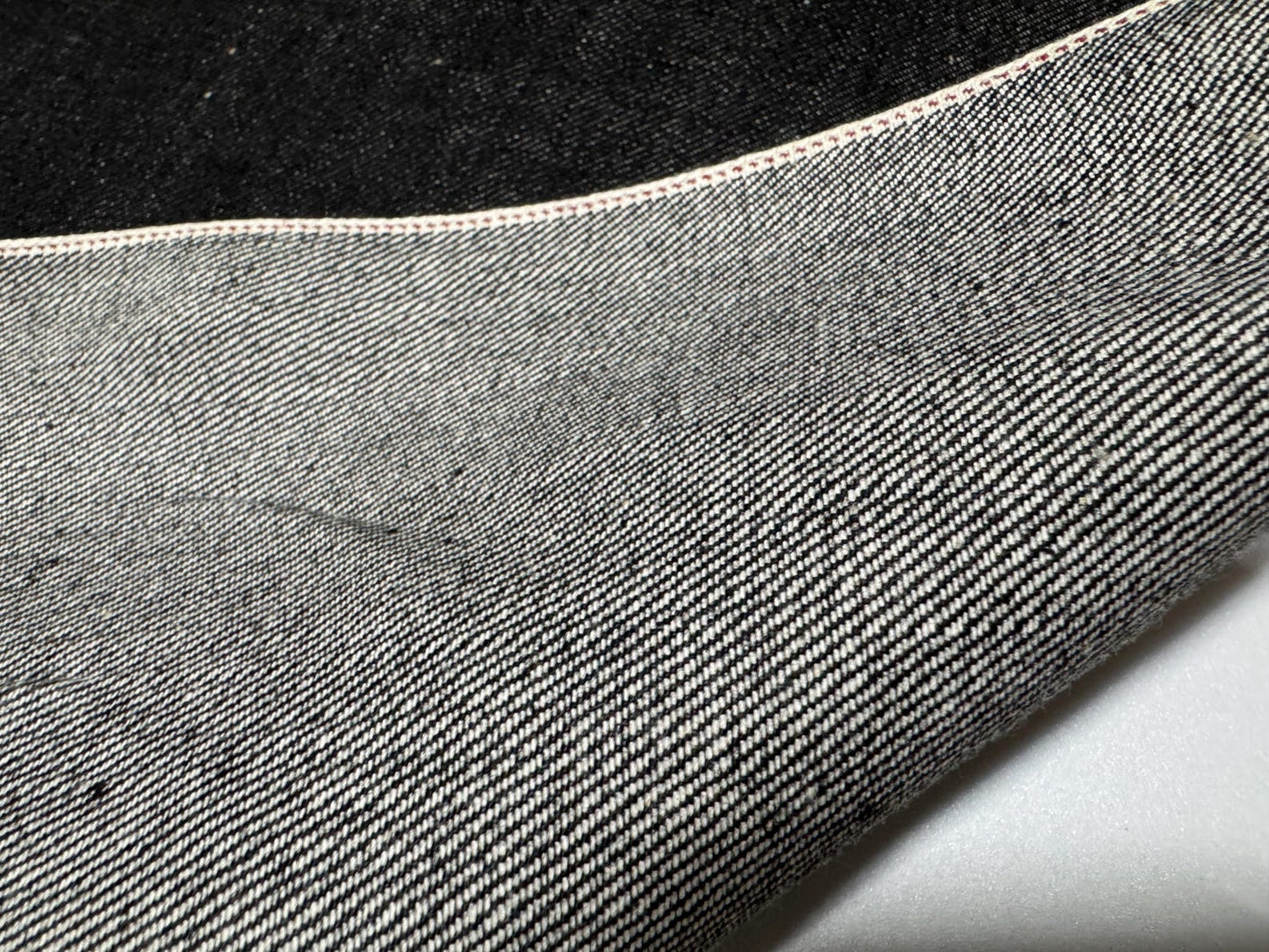 Close-up of Okayama Denim 10.5 oz black selvage fabric showcasing its smooth texture and durable weave.