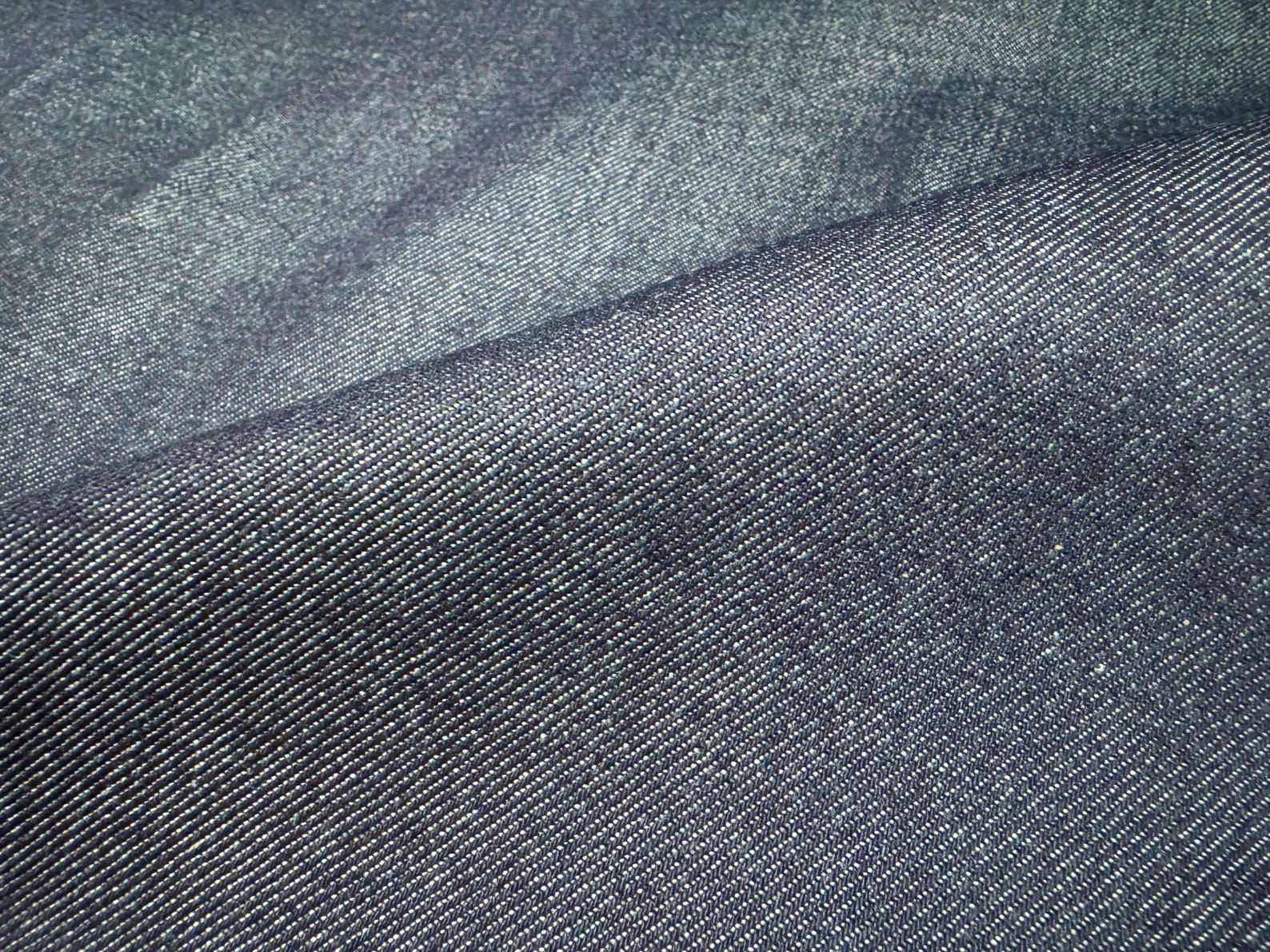 Close-up of Okayama Denim, 10.5 oz Japanese Indigo Selvage Denim showcasing its smooth texture and dark indigo color.