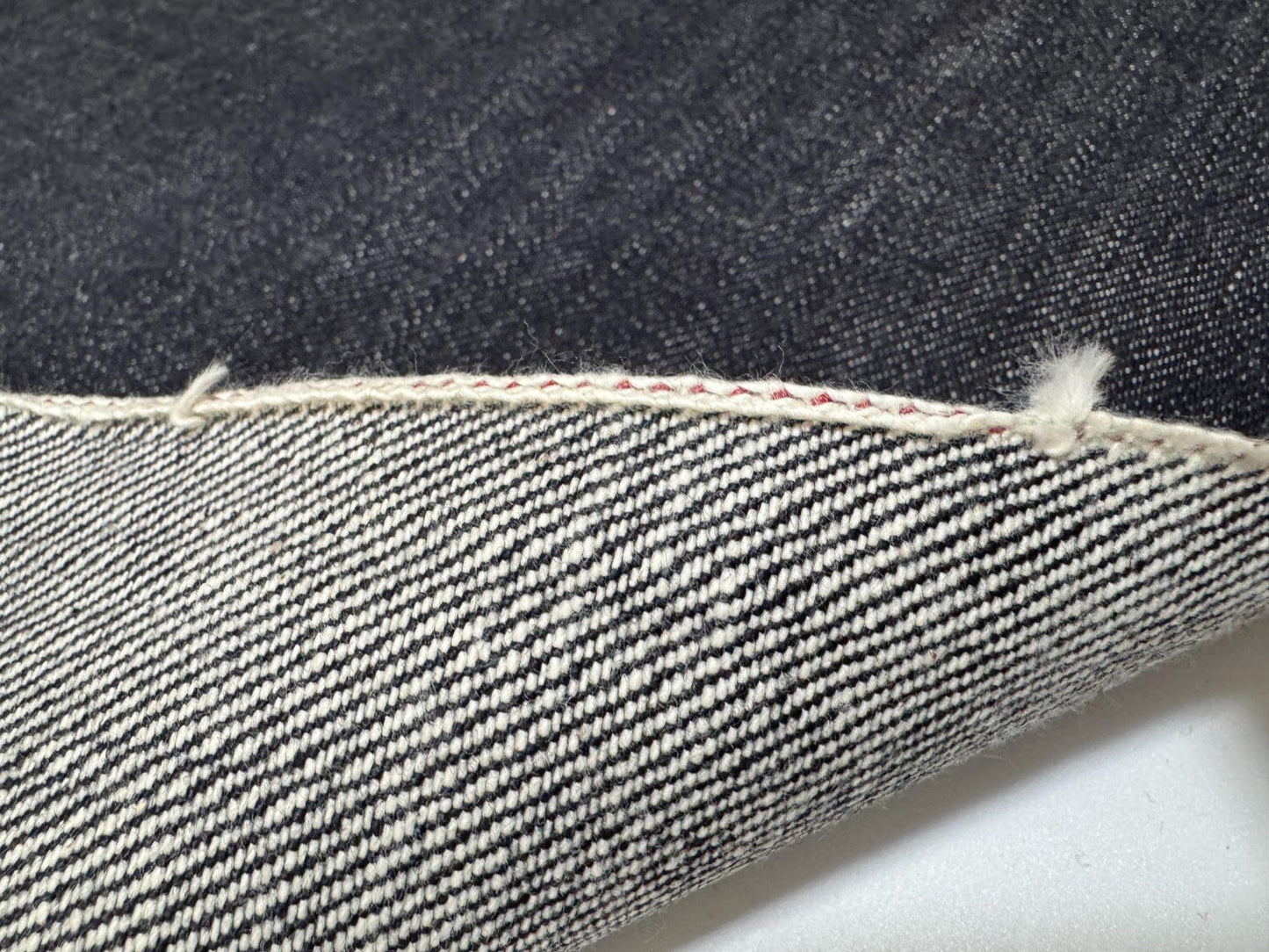 Okayama Denim close-up of 19.5 oz Japanese Heavy Ounce Indigo Selvage denim fabric showcasing its unique texture and selvage edge.