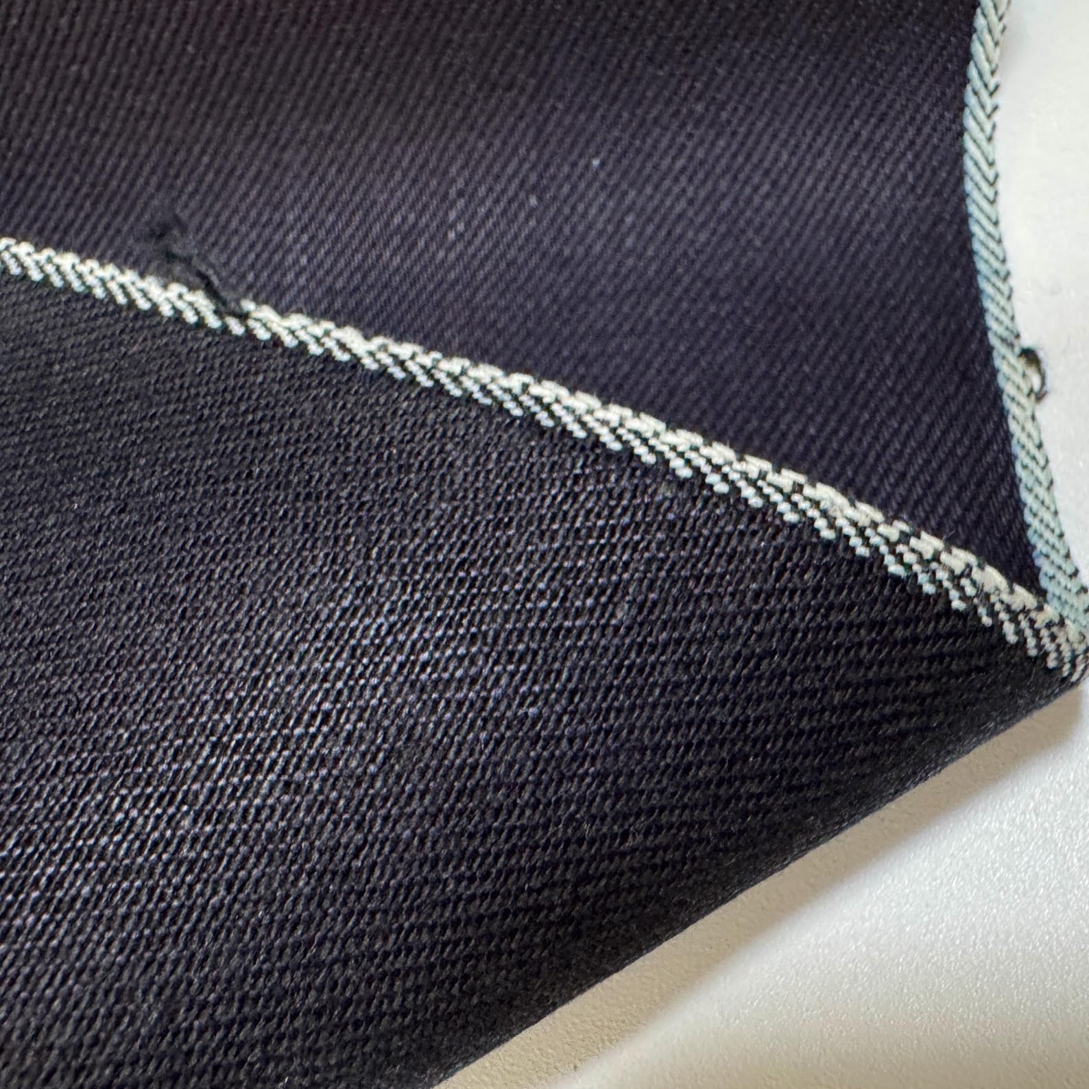 Okayama Denim 12 oz double-sided indigo selvage fabric with white stitching detail on the edge.