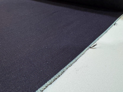 Close-up of Okayama Denim, 12 oz double-sided indigo selvage fabric showcasing the smooth navy blue texture and edge details.