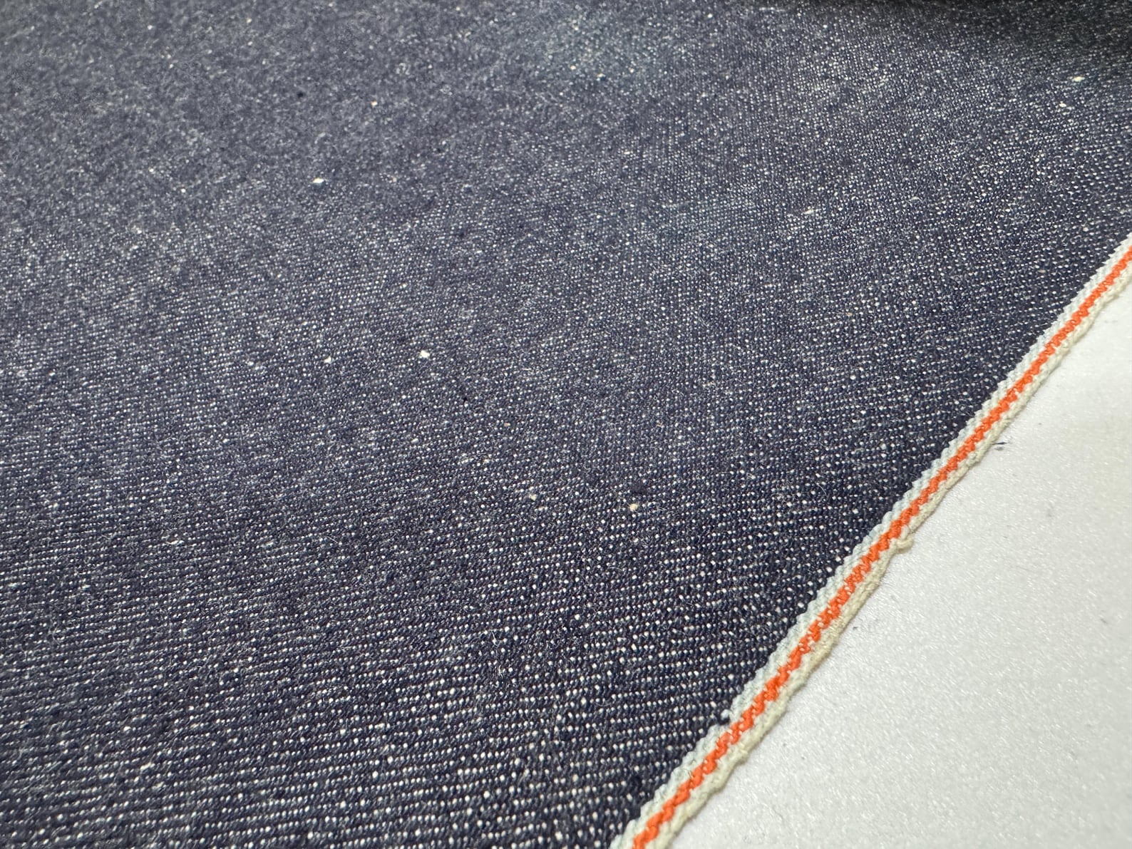 Okayama Denim 13 oz indigo kibata Japanese selvedge denim fabric showing orange selvage edge.