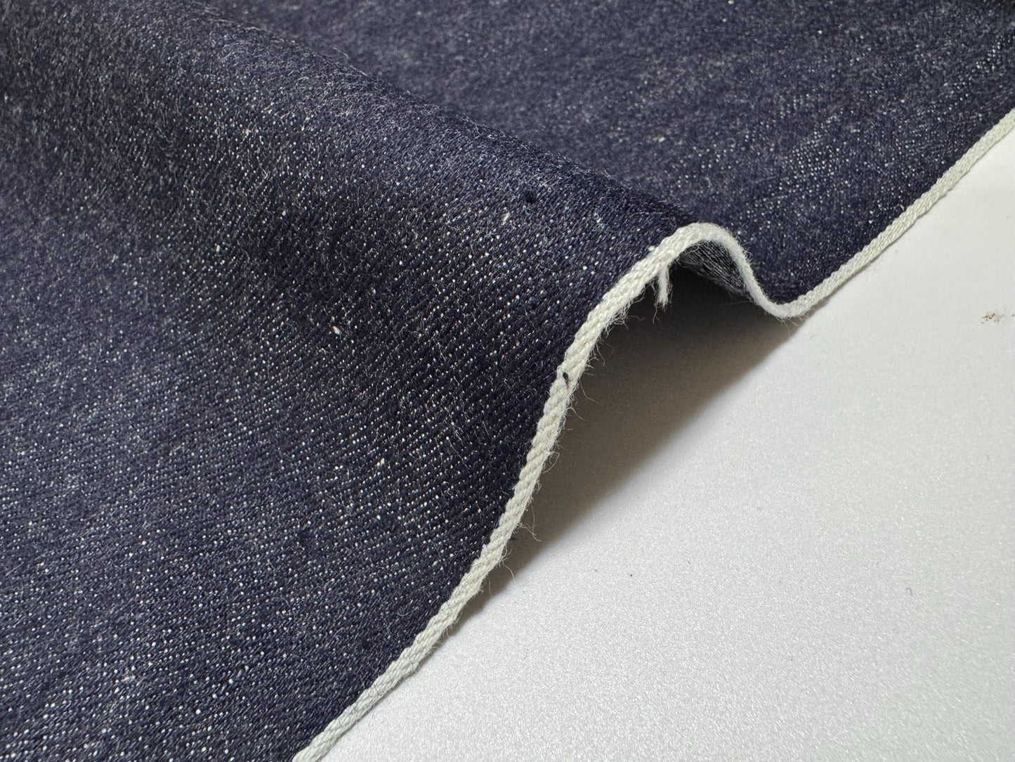 Okayama Denim | 11.5oz indigo rigid selvage Japanese denim fabric showcasing smooth texture and dark blue color.