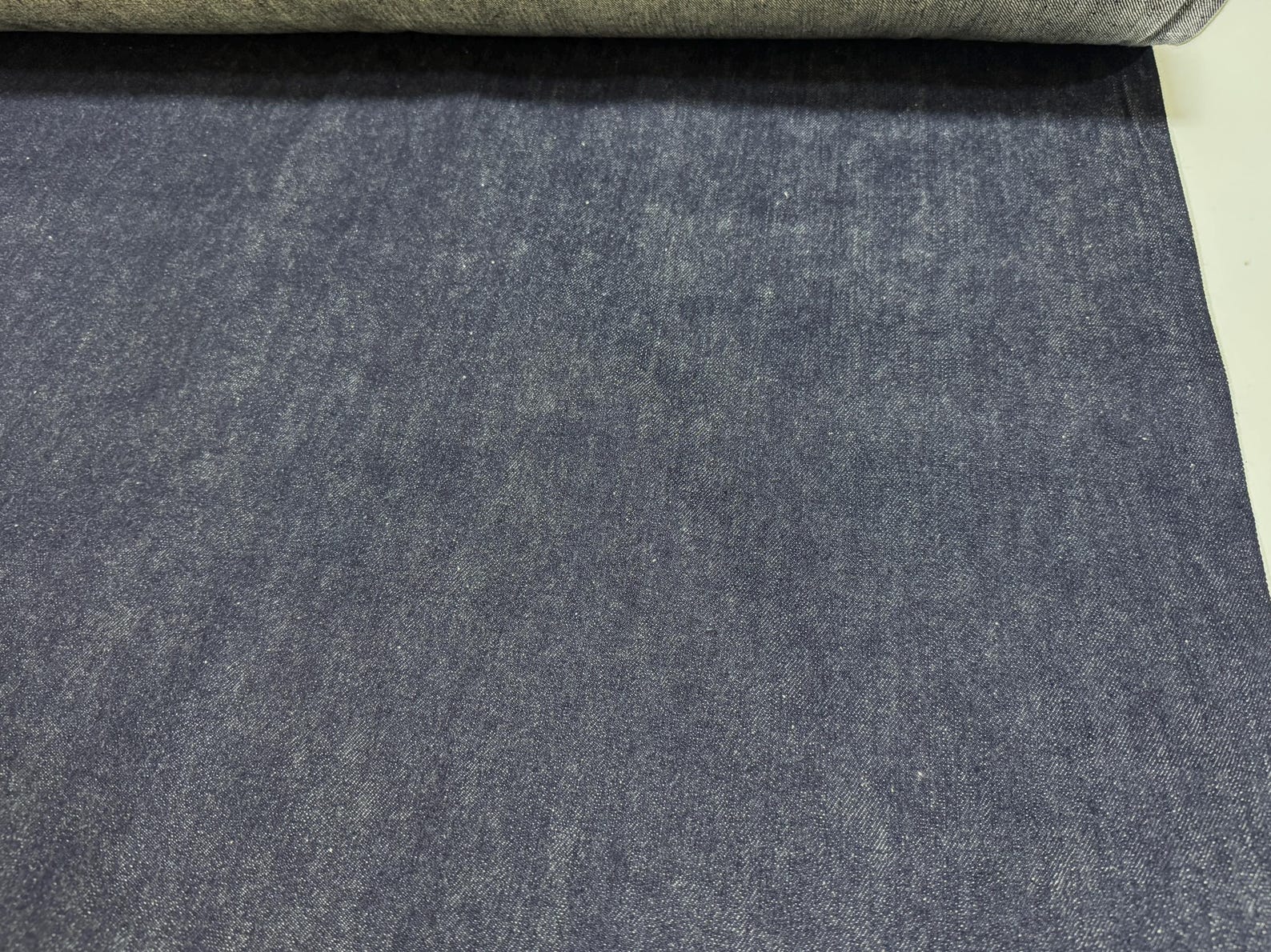 Okayama Denim | 11.5oz indigo rigid selvage Japanese denim fabric rolled out on a table.