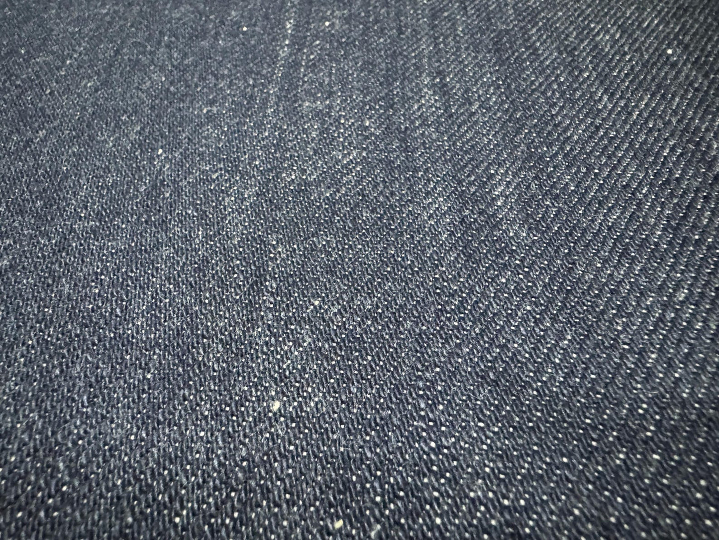 Close-up of Okayama Denim fabric showcasing the texture of 21 oz Japanese heavy ounce indigo selvage denim.