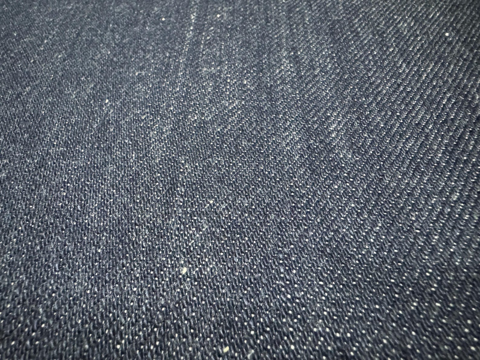 Close-up of Okayama Denim fabric showcasing the texture of 21 oz Japanese heavy ounce indigo selvage denim.