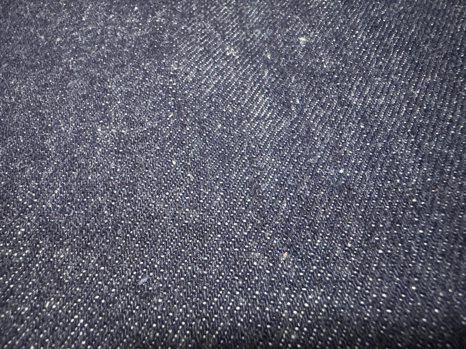 Okayama Denim 11.5oz indigo rigid selvage Japanese denim fabric close-up showing its smooth texture and dark blue color.