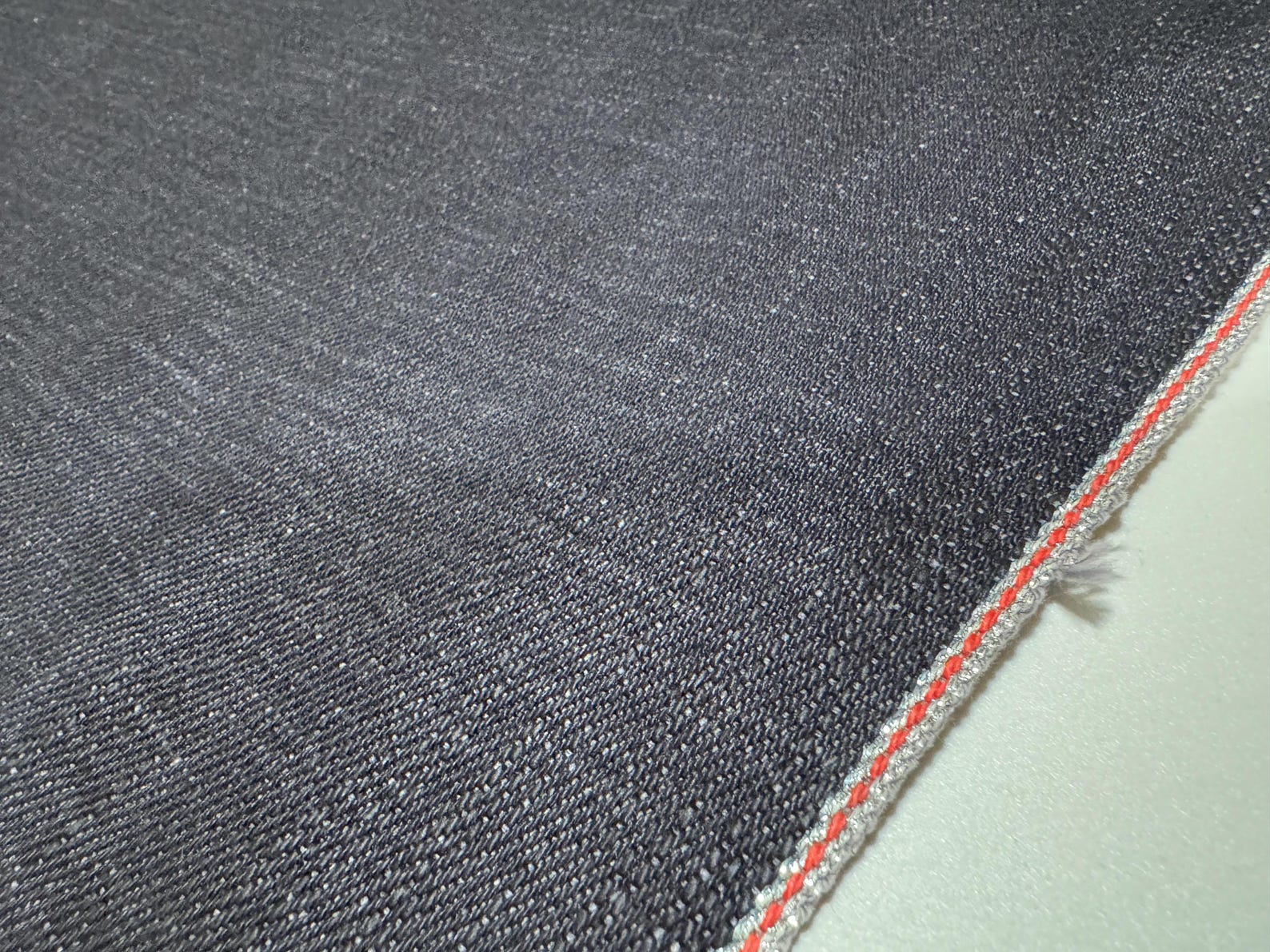 Okayama Denim showcasing 20 oz heavy-ounce Japanese selvage indigo fabric with red selvedge detail.
