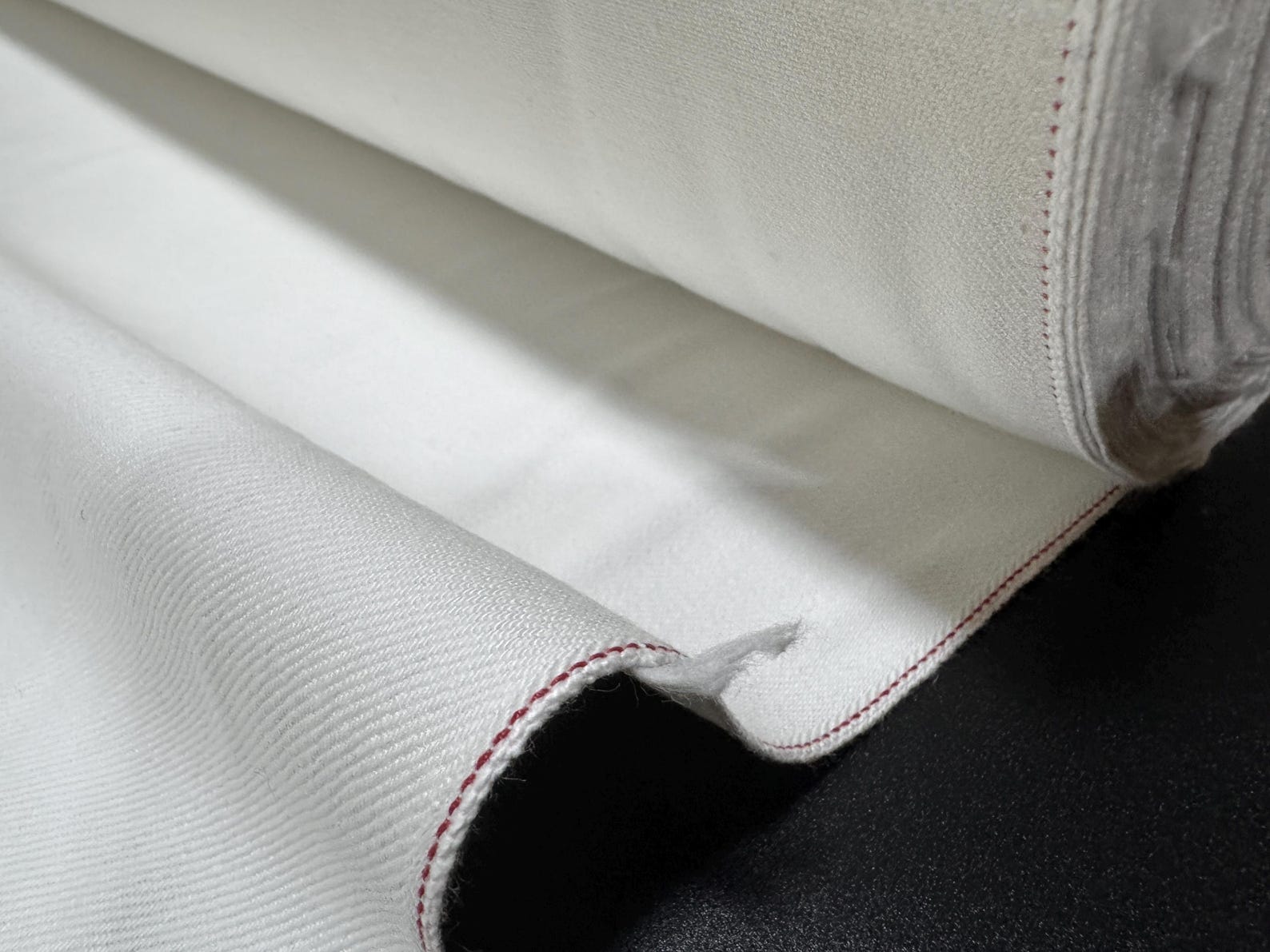 Okayama Denim 13 oz White Selvedge fabric roll with red edge showcasing premium Japanese craftsmanship.