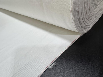 Okayama Denim 13 oz White Selvedge fabric with red edge rolled on a black surface.