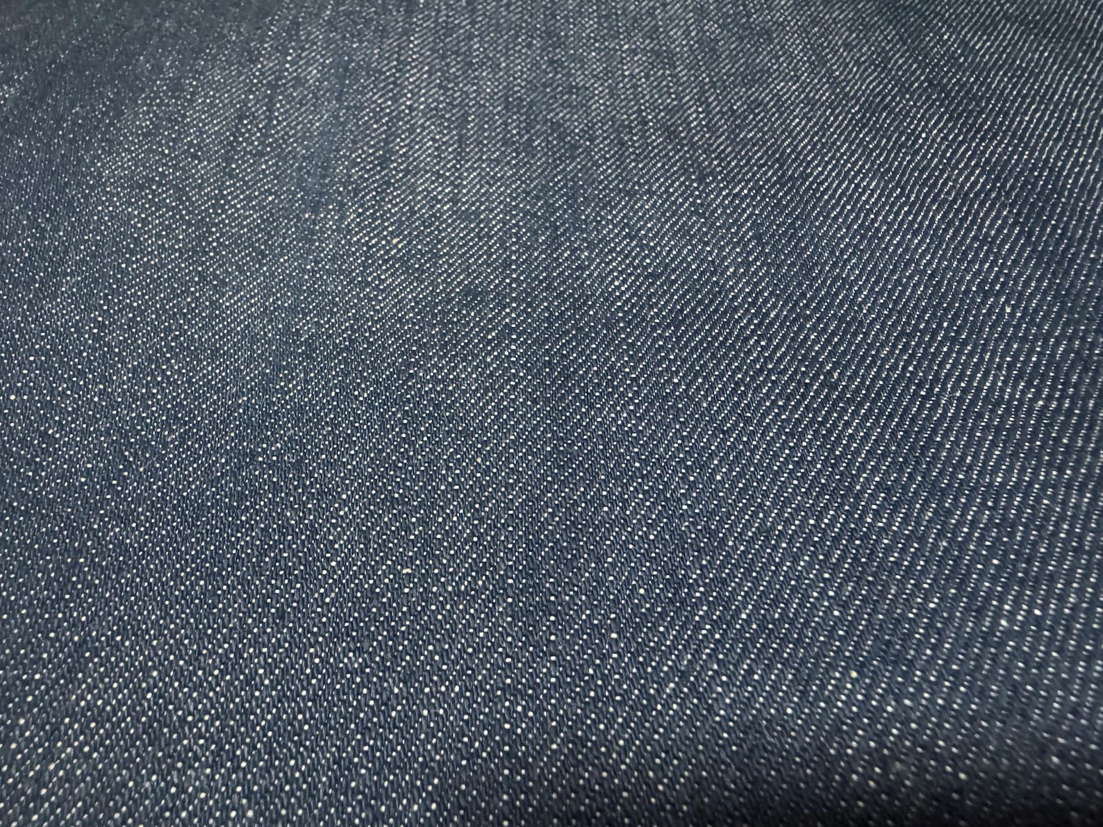 Okayama Denim fabric close-up showing the texture of 12.5 oz double width indigo Japanese denim.