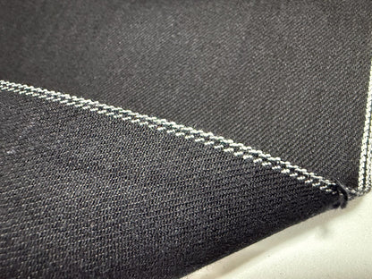 Okayama Denim 11oz double-sided black Japanese selvage fabric showcasing smooth texture and distinctive stitching.