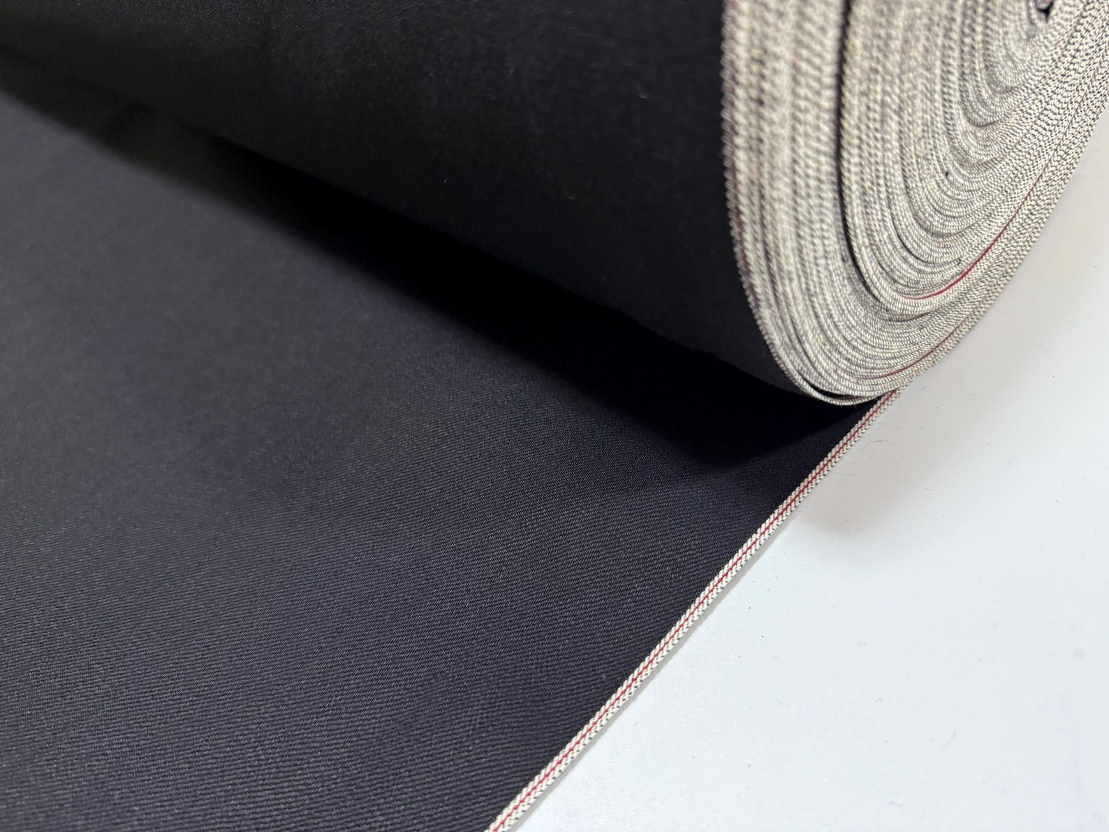 Okayama Denim | 11oz double-sided black Japanese selvage fabric roll showcasing premium quality and smooth texture.