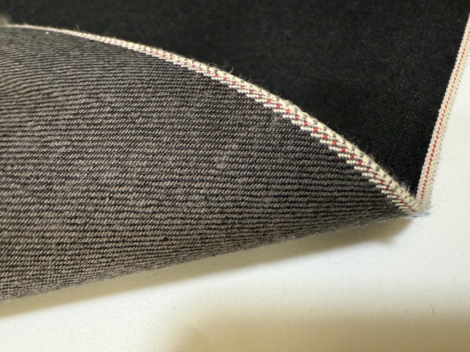 Okayama Denim | 13.5oz black/gray Japanese Selvage Denim fabric showcasing a smooth texture and unique weave.